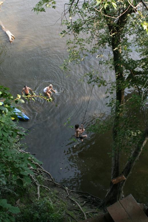 Young adults on a Conneticuit River Rope swing, Aug, 2009, North Hampton, MA at the Railtrail bridge.