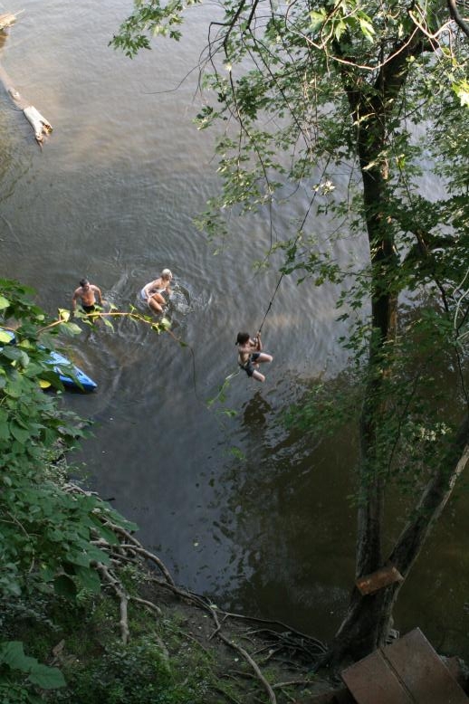 Young adults on a Conneticuit River Rope swing, Aug, 2009, North Hampton, MA at the Railtrail bridge.