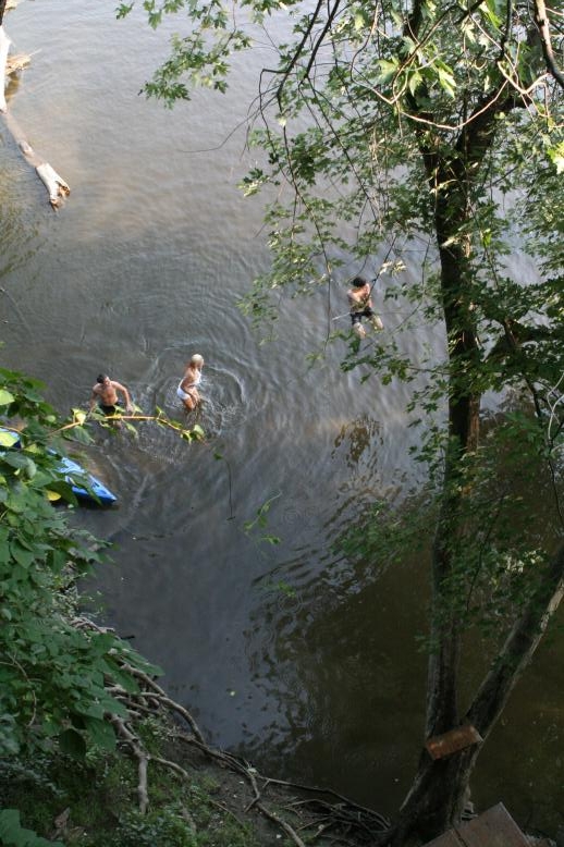 Young adults on a Conneticuit River Rope swing, Aug, 2009, North Hampton, MA at the Railtrail bridge.