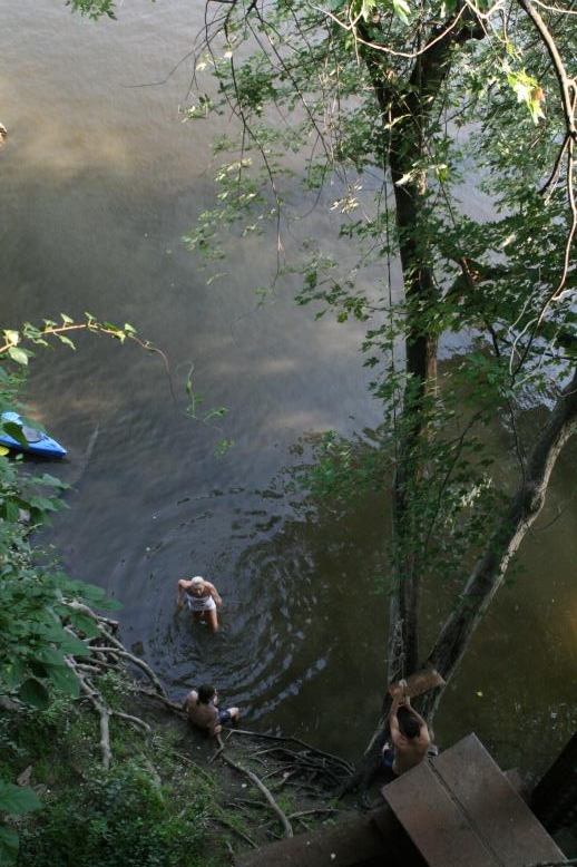 Young adults on a Conneticuit River Rope swing, Aug, 2009, North Hampton, MA at the Railtrail bridge.