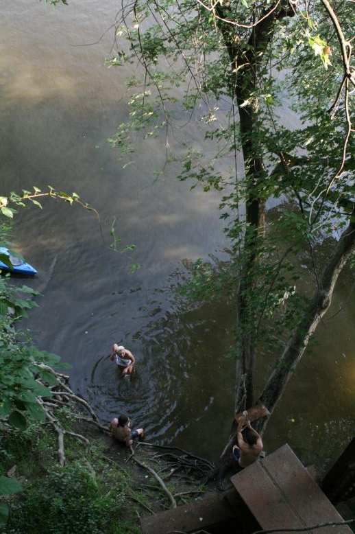 Young adults on a Conneticuit River Rope swing, Aug, 2009, North Hampton, MA at the Railtrail bridge.