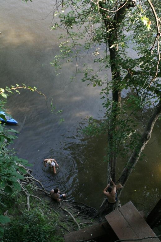 Young adults on a Conneticuit River Rope swing, Aug, 2009, North Hampton, MA at the Railtrail bridge.