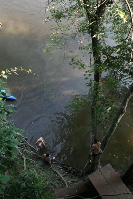 Young adults on a Conneticuit River Rope swing, Aug, 2009, North Hampton, MA at the Railtrail bridge.