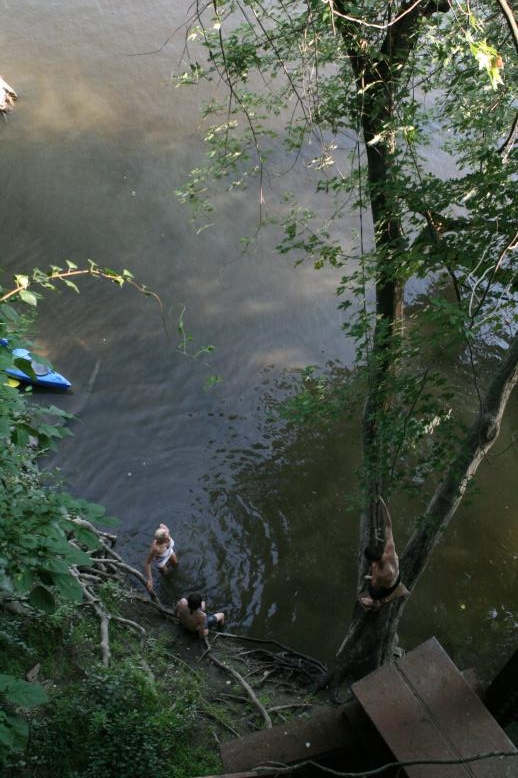 Young adults on a Conneticuit River Rope swing, Aug, 2009, North Hampton, MA at the Railtrail bridge.