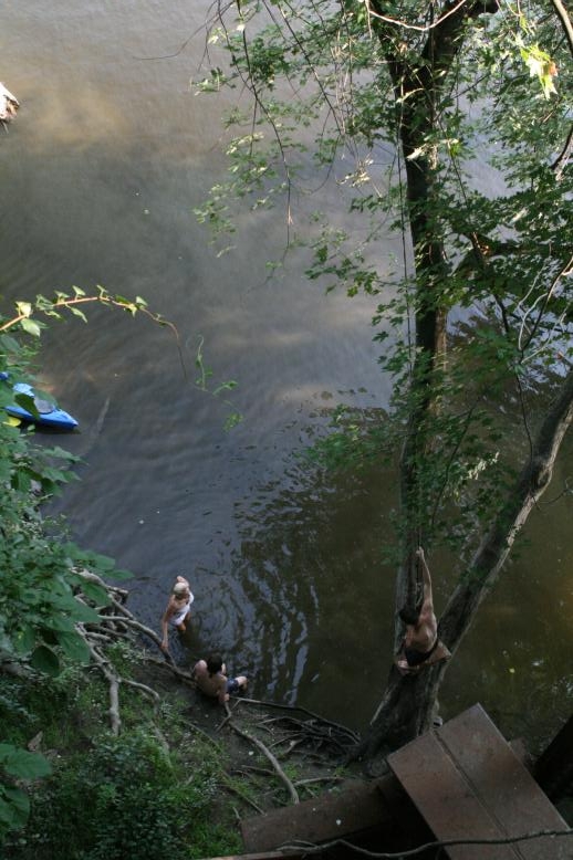 Young adults on a Conneticuit River Rope swing, Aug, 2009, North Hampton, MA at the Railtrail bridge.