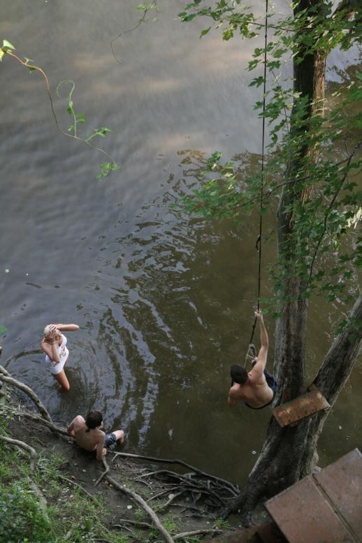 Young adults on a Conneticuit River Rope swing, Aug, 2009, North Hampton, MA at the Railtrail bridge.