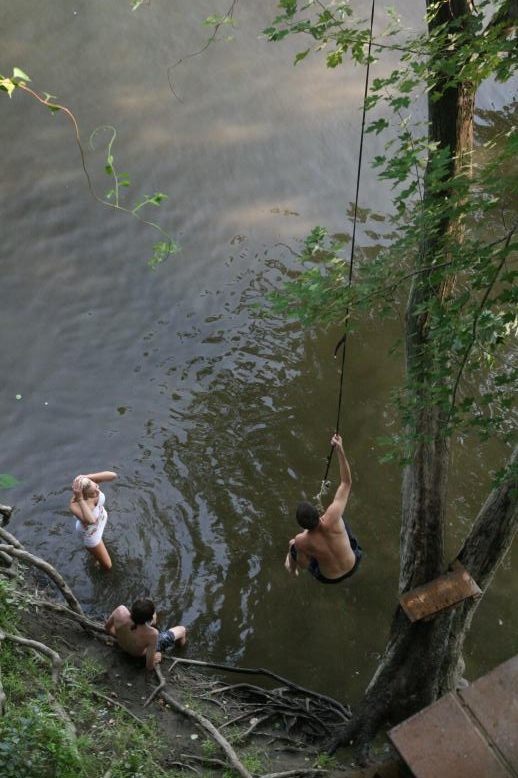 Young adults on a Conneticuit River Rope swing, Aug, 2009, North Hampton, MA at the Railtrail bridge.