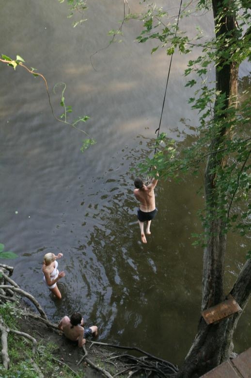 Young adults on a Conneticuit River Rope swing, Aug, 2009, North Hampton, MA at the Railtrail bridge.