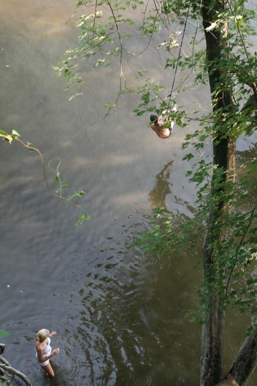 Young adults on a Conneticuit River Rope swing, Aug, 2009, North Hampton, MA at the Railtrail bridge.