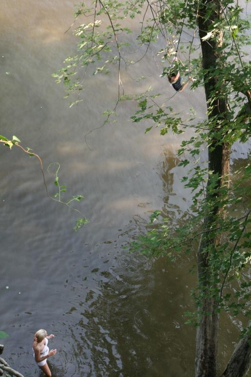 Young adults on a Conneticuit River Rope swing, Aug, 2009, North Hampton, MA at the Railtrail bridge.