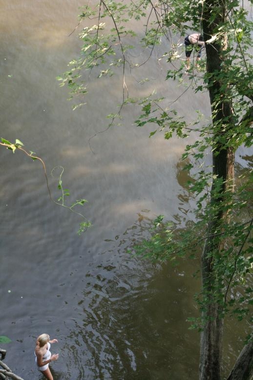 Young adults on a Conneticuit River Rope swing, Aug, 2009, North Hampton, MA at the Railtrail bridge.