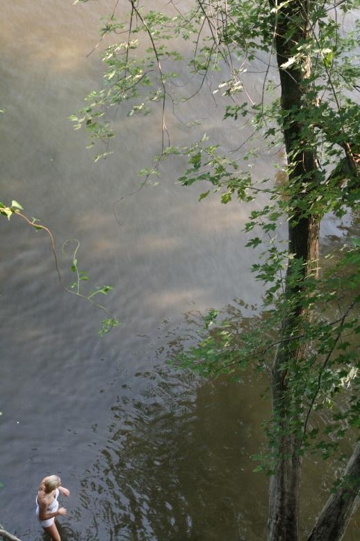 Young adults on a Conneticuit River Rope swing, Aug, 2009, North Hampton, MA at the Railtrail bridge.