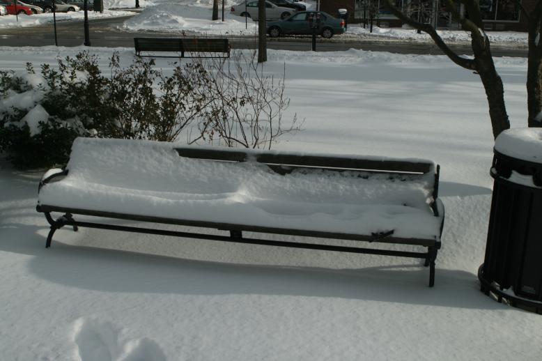 Snow covered bench.  Drifts of snow make parallel patterns of waves.  Sunlight gives stark contrast. Wellesley, MA , Jan 3, 2009.