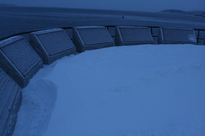 Always remembered, even covered in snow. Fisherman's Memorial, Glochestor, MA  Jan 3, 2009.  Very large waves crash below the bluff in a turbulent ocean.  