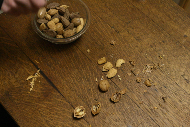 Hammer in motion over a dark stained antique oak desk on a Winter's day 2011. The hammer is outside the frame in this shot.  There are various cracked nuts on the desktop:  Walnuts, Almonds, and various shells.