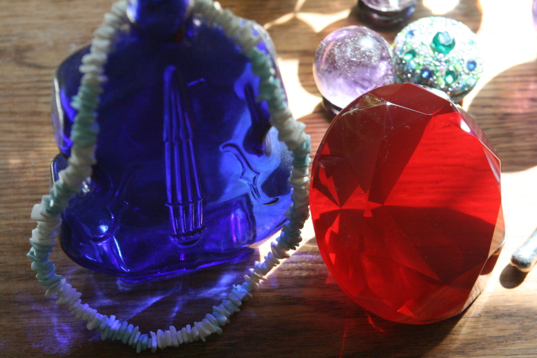 The Red Ruby of passion. The Cobolt blue fiddle-bottle is Serenity. The necklace is all that surrounds Serenity, the things we create to mark and note it. The amythist sphere is the temporate revelry. The Emerald on the box is the emblem of mystic love. Sunlight shines brightly on the famous table. copyright © 2011. 